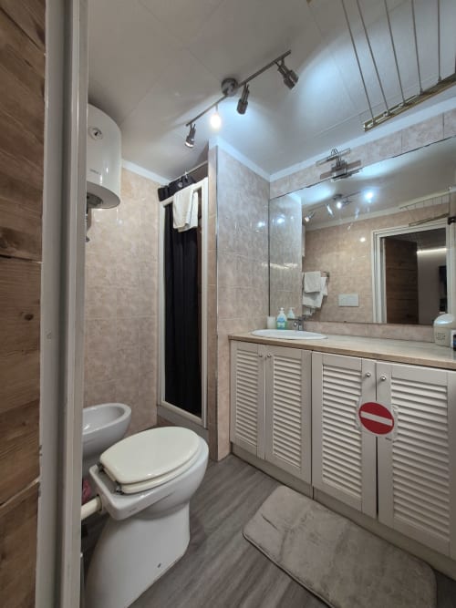 Bagno moderno nell'appartamento Nidus di Giulia, Roma - lavabo con specchio, doccia, wc, pareti piastrellate, illuminazione a binario