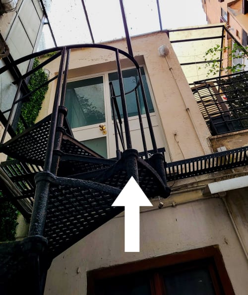 Scala e balconata in metallo nero dell'appartamento Nidus di Giulia a Roma con vista sulla città e terrazza