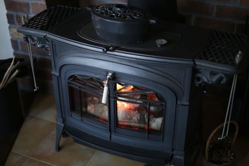 Poêle en bois noir avec feu rougeoyant à La Grange Aux Étangs, un gîte chaleureux à Sennely, France