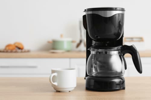 Cafetière à drippage noire avec tasse blanche sur comptoir en bois à La Grange Aux Etangs B&B à Sennely