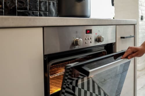 Personne ouvrant la porte du four dans la cuisine du gîte La Grange Aux Étangs à Sennely, France