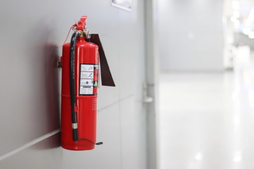 Extincteur rouge fixé au mur blanc à La Grange Aux Étangs, gîte à Sennely