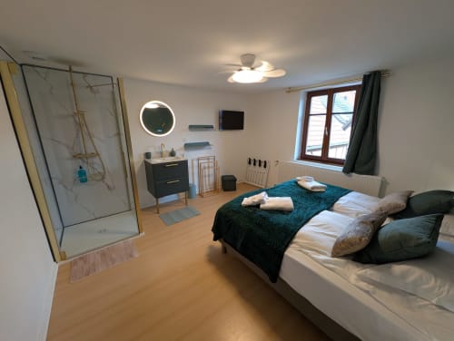 Modern bedroom at Bi d'Grosseltere in Kirrwiller with ensuite bathroom, bed, desk, and garden view window