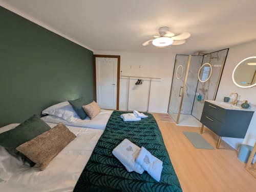 Modern cottage bedroom at Bi d'Grosseltere in Kirrwiller with green accent wall, queen bed, wood floors, and ensuite bathroom