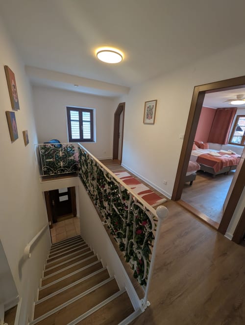 Landing of Bi d'Tante Irène cottage with stairs, decorative railing, and bedroom view at Bi d'Grosseltere B&B in Kirrwiller