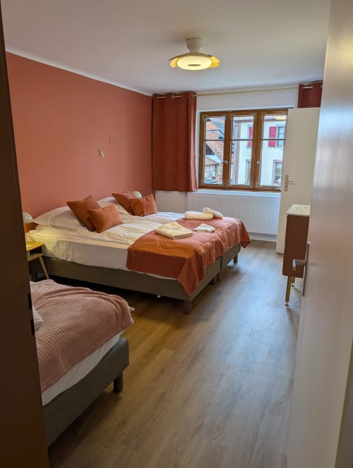 Modern bedroom at Bi d'Grosseltere in Kirrwiller with two beds, terracotta walls, wooden floor and garden views