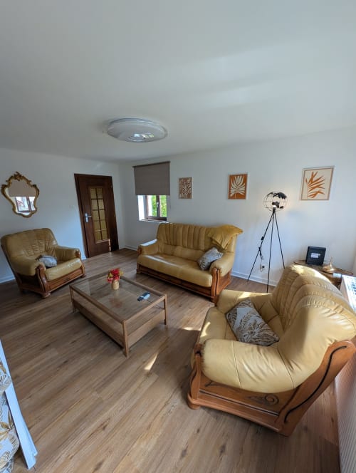 Spacious living room at Bi d'Tante Irène cottage in Kirrwiller with cream leather furniture, wooden coffee table, and garden