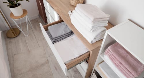 Rangement organisé à La Grange Aux Etangs : serviettes blanches et roses pliées dans les tiroirs et étagères, bois moderne