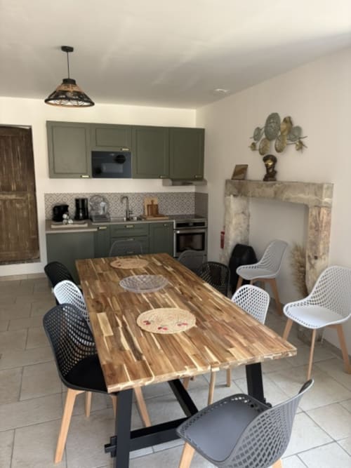 Salle à manger moderne avec table en bois, chaises variées, cuisine olive, foyer et luminaires suspendus