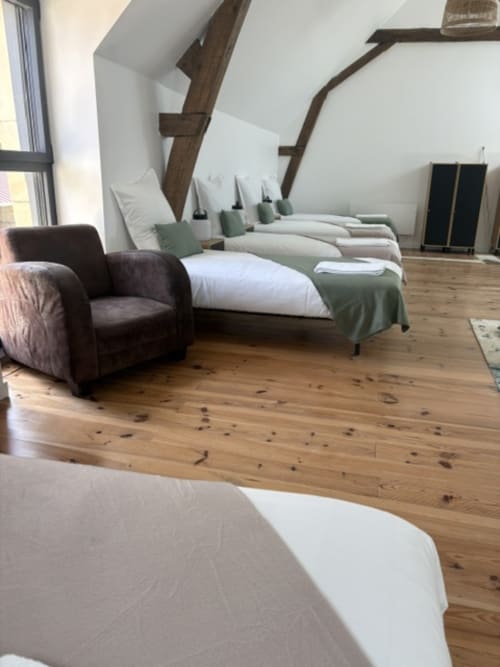 Chambre de dortoir spacieuse au Domaine Du Grand Fort avec plusieurs lits, poutres en bois et décor rustique à Banneville la