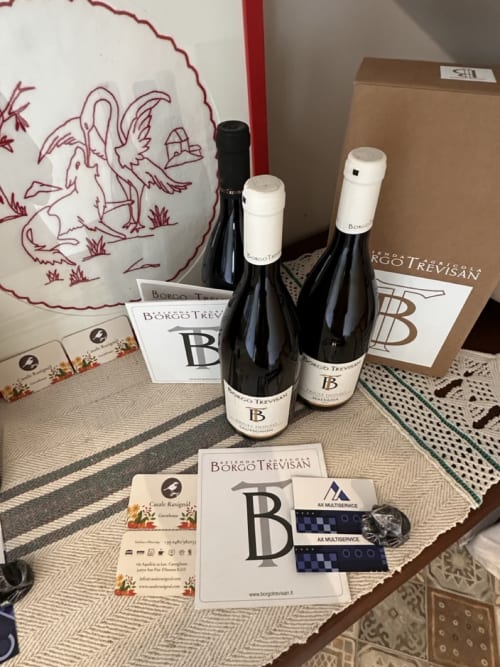 Bottiglie di vino Borgo Trevisan e materiali promozionali esposti durante l'evento di ospitalità Casale Rusignûl in Italia