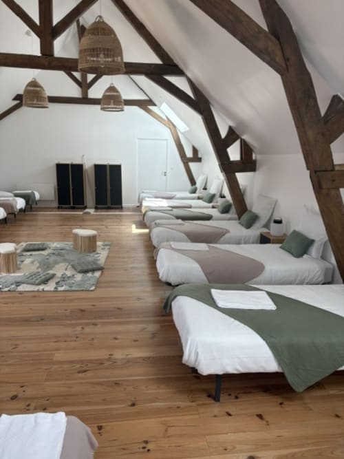 Dortoir spacieux de 14 personnes au Domaine Du Grand Fort avec poutres en bois apparent, lits individuels avec couvertures vertes, en bois