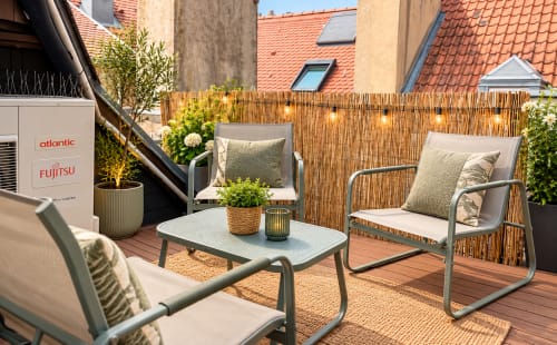 Terrasse ensoleillée sur le toit avec coin détente, plantes et vue sur la ville, appartement à Metz