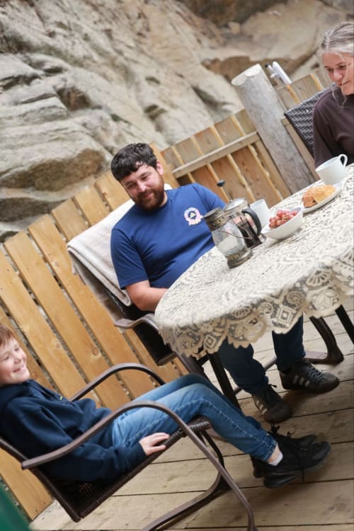 Family enjoying outdoor meal at Greenvale Cabins in Newry with stone cliffs backdrop