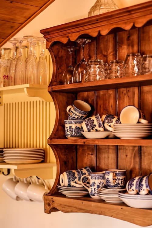 Rustic wooden dresser with blue and white ceramic dinnerware and glassware at Greenvale Cabins, Newry