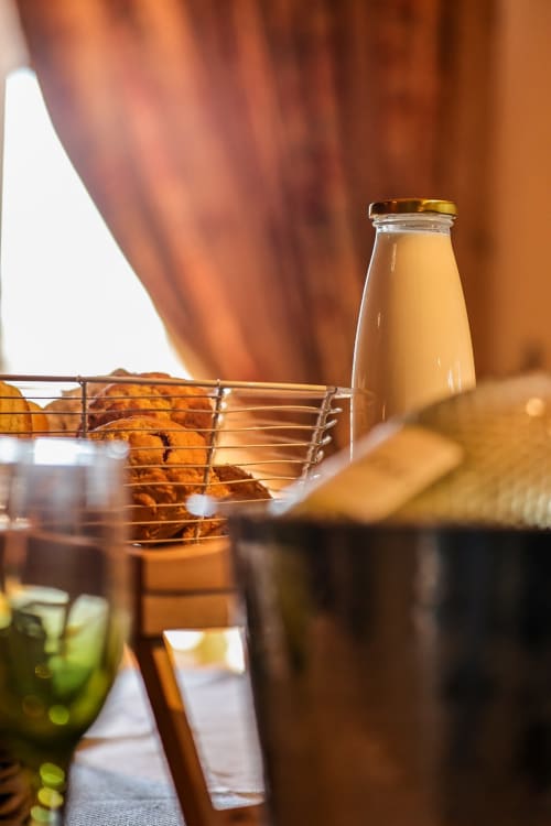 Warm afternoon drinks at Greenvale Cabins: beer bottle, juice glasses, and appetizers on a metal rack with mountain view