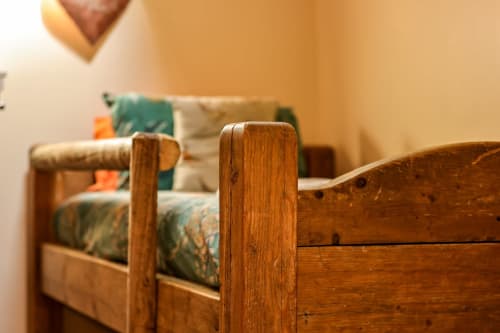 Rustic wooden bed frame with green patterned bedding at Greenvale Cabins Colorado Apartment in Newry
