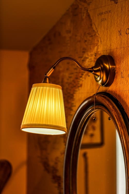 Vintage brass wall sconce with pleated cream shade in Colorado Apartment at Greenvale Cabins, Newry
