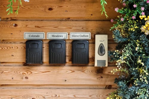 Three black doorbells labeled Colorado, Meadows, and Sieve Gullion mounted on wooden cabin wall at Greenvale Cabins, Newry
