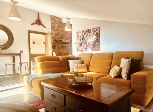 Cozy sitting area at Greenvale Cabins with golden-orange sectional sofa, wooden coffee table, and modern pendant lights in