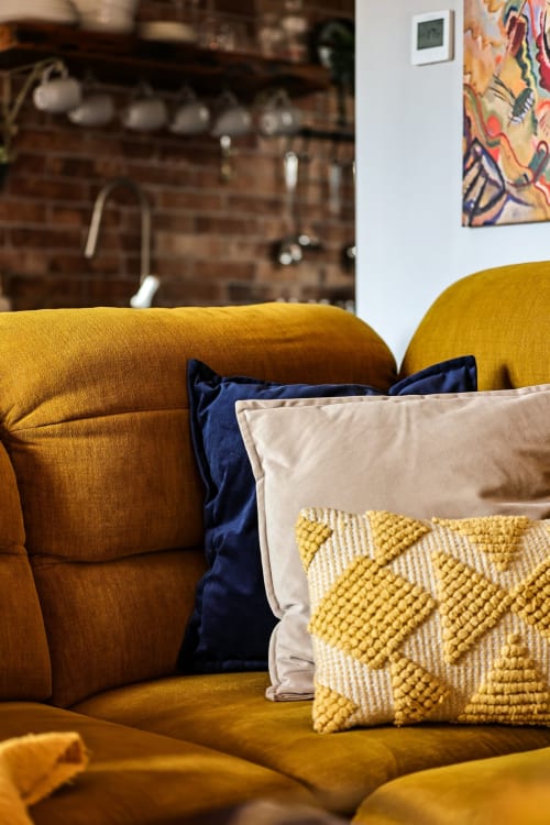 Mustard yellow armchair with blue and cream decorative pillows in Slieve Gullion Apartment sitting area at Greenvale Cabins,
