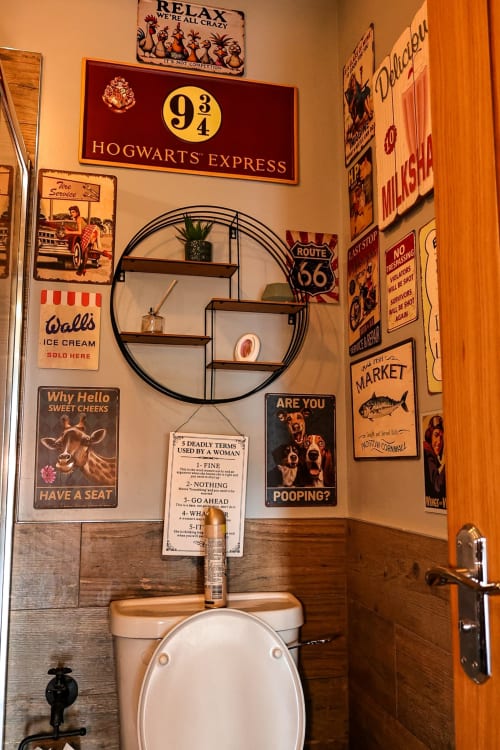 Themed bathroom toilet at Greenvale Cabins featuring vintage signs and pop culture decor on walls