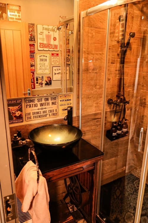 Bathroom at Greenvale Cabins with black vessel sink, wood vanity, shower enclosure, vintage decor, and towel rack in Newry