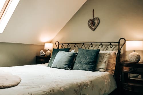 Cozy bedroom at Greenvale Cabins with wrought iron bed, decorative pillows, garden view, and skylights in Newry