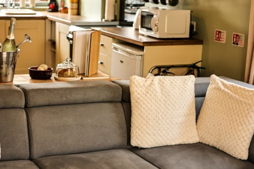 Greenvale Apartment sitting area with gray sofa, cream pillows, and champagne bucket overlooking kitchen