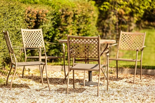 Garden seating area at Greenvale Cabins with metal chairs and small table surrounded by green hedges in Newry