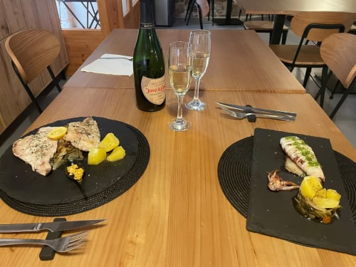 Taula de menjador elegant al restaurant L'Algars de Cáceres amb peix, patates i xampany a Tarragona.