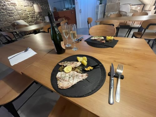 Taula d'alta cuina a L'Algars amb peix a la brasa, verdures, copes de vi i coberts a Cáceres