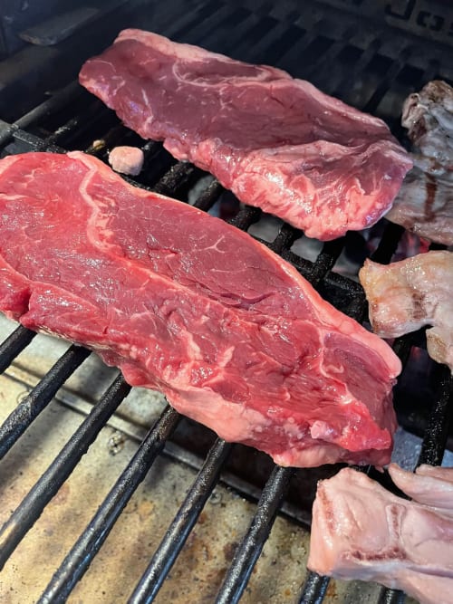 Diversos bistecs crus a la brasa en la barbacoa del restaurant L'Algars a Tarragona