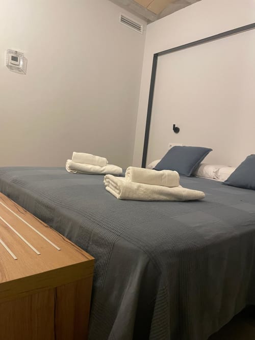 Habitació Cariñena de l'hotel boutique L'Algars a Cáceres amb tovalloles enrollades sobre llit fosc