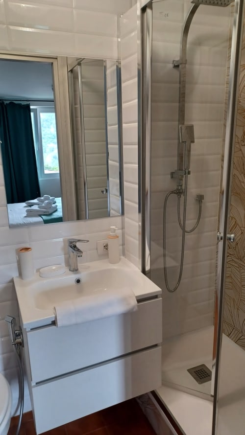 Bagno moderno con vanity bianca, specchio e cabina doccia in vetro della collezione THE V a Milano