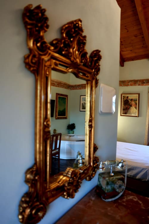 Specchio dorato ornamentale nella suite di B&B Cascina Tavella a Rivalta di Torino, che riflette l'elegante interno della camera