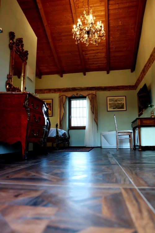 Elegante suite di B&B Cascina Tavella a Rivalta di Torino con travi in legno a vista, lampadario di cristallo e legno lucidato
