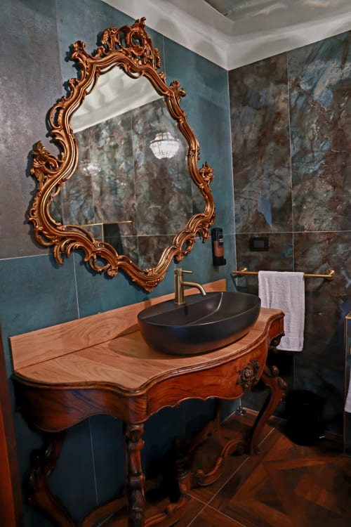 Elegante bagno del B&B Cascina Tavella con specchio dorato ornamentale, lavabo scuro in marmo turchese su vanity in legno.
