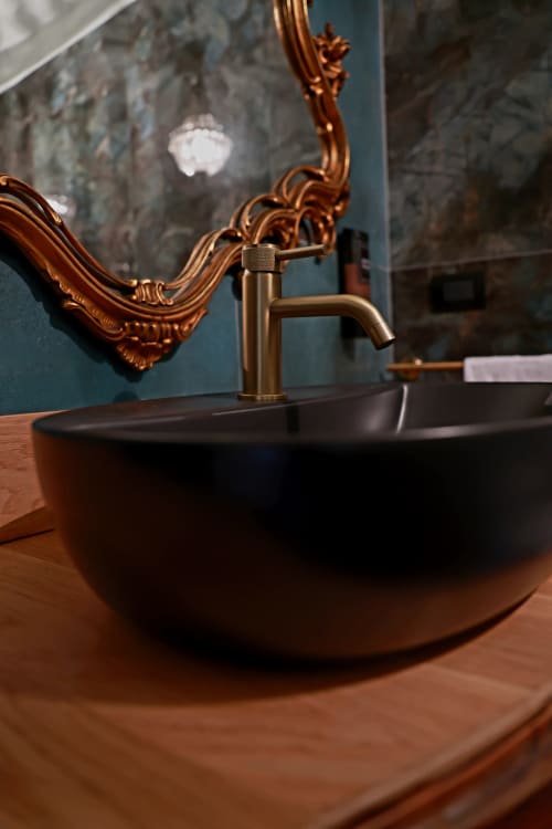 Lavabo nero moderno con rubinetto in ottone e specchio in rame ornamentale nella suite del B&B Cascina Tavella, Rivalta di Torino