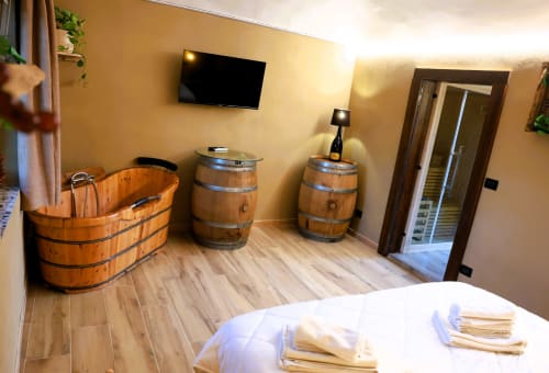 Camera a tema botte in legno presso B&B Cascina Tavella con vasca in legno, arredi a botte e letto bianco a Rivalta di