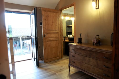 Camera da letto con cassettone in legno, specchio, balcone aperto e bagno privato presso B&B Cascina Tavella a Rivalta di Torino