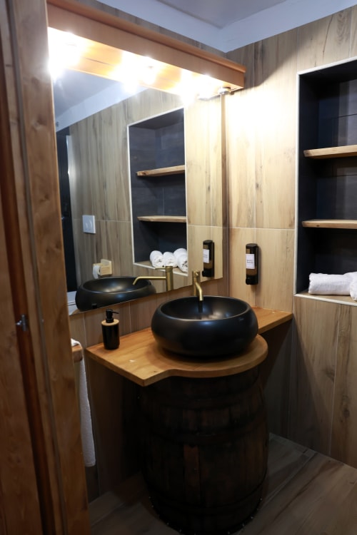 Bagno moderno del B&B Cascina Tavella con lavabo nero, vanità in legno, specchio ampio e ripiani a muro