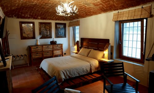 Camera rustica della B&B Cascina Tavella con letto in legno, soffitto in laterizio a vista e vista sulla campagna dalle porte vetrate