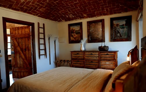 Camera rustica al B&B Cascina Tavella con soffitto a travi in laterizio, mobili in legno e opere d'arte incorniciate a Rivalta di Torino