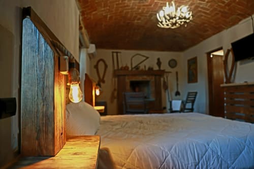 Camera rustica al B&B Cascina Tavella con testata in legno, illuminazione calda e il fascino della campagna a Rivalta di Torino
