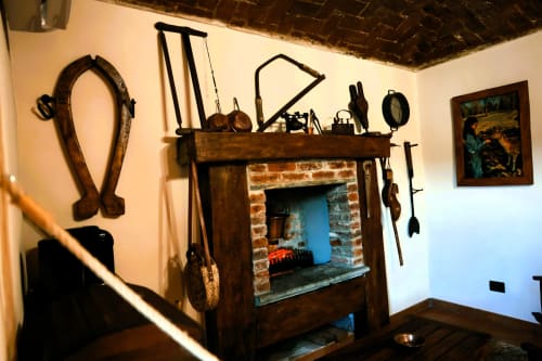 Camino rustico con attrezzi tradizionali e attrezzature di cucina nella Camera del Contadino di B&B Cascina Tavella, Rivalta