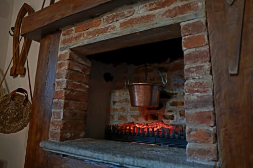 Storico camino con braci ardenti e pentola di rame a B&B Cascina Tavella a Rivalta di Torino