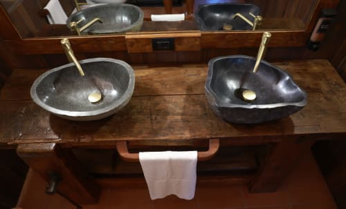 Due lavabi in pietra scura con rubinetti in ottone su vanità in legno presso B&B Cascina Tavella a Rivalta di Torino