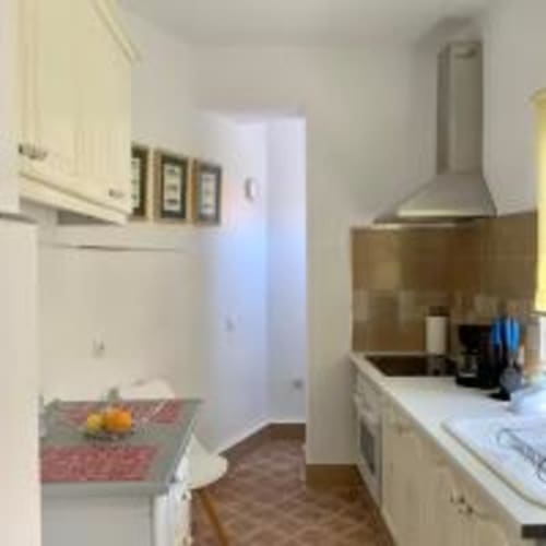 Moderna cocina en apartamento de Tenerife con gabinetes blancos, campana extractora de acero inoxidable y vistas a la ciudad