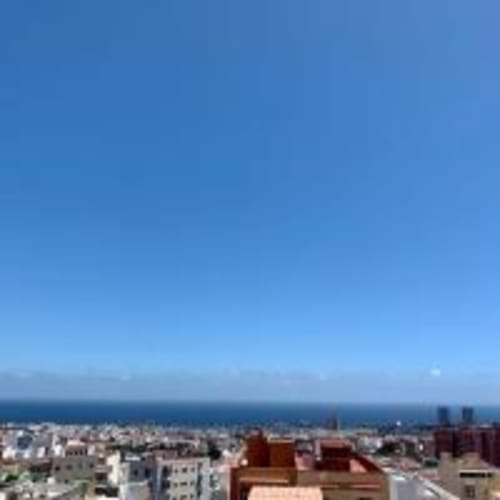 Vista aérea de Santa Cruz de Tenerife y su costa desde el balcón de un apartamento con cielo azul y horizonte oceánico